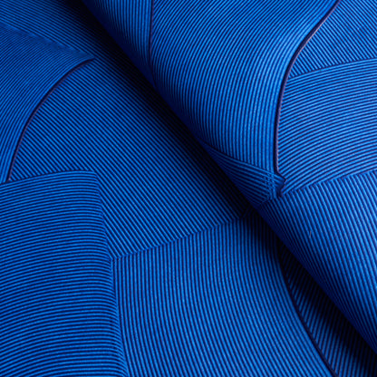 Royal blue ribbed upholstery fabric with stitched seams and curved folds, fine vertical stripe texture.