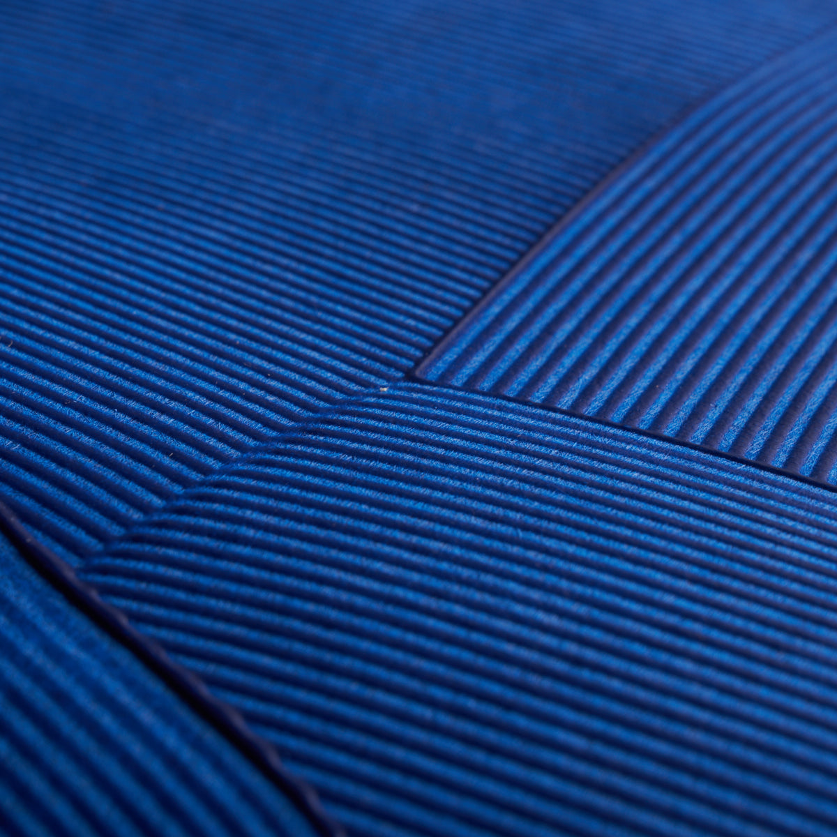 Close-up of blue corduroy fabric with ribbed texture and diagonal seam.