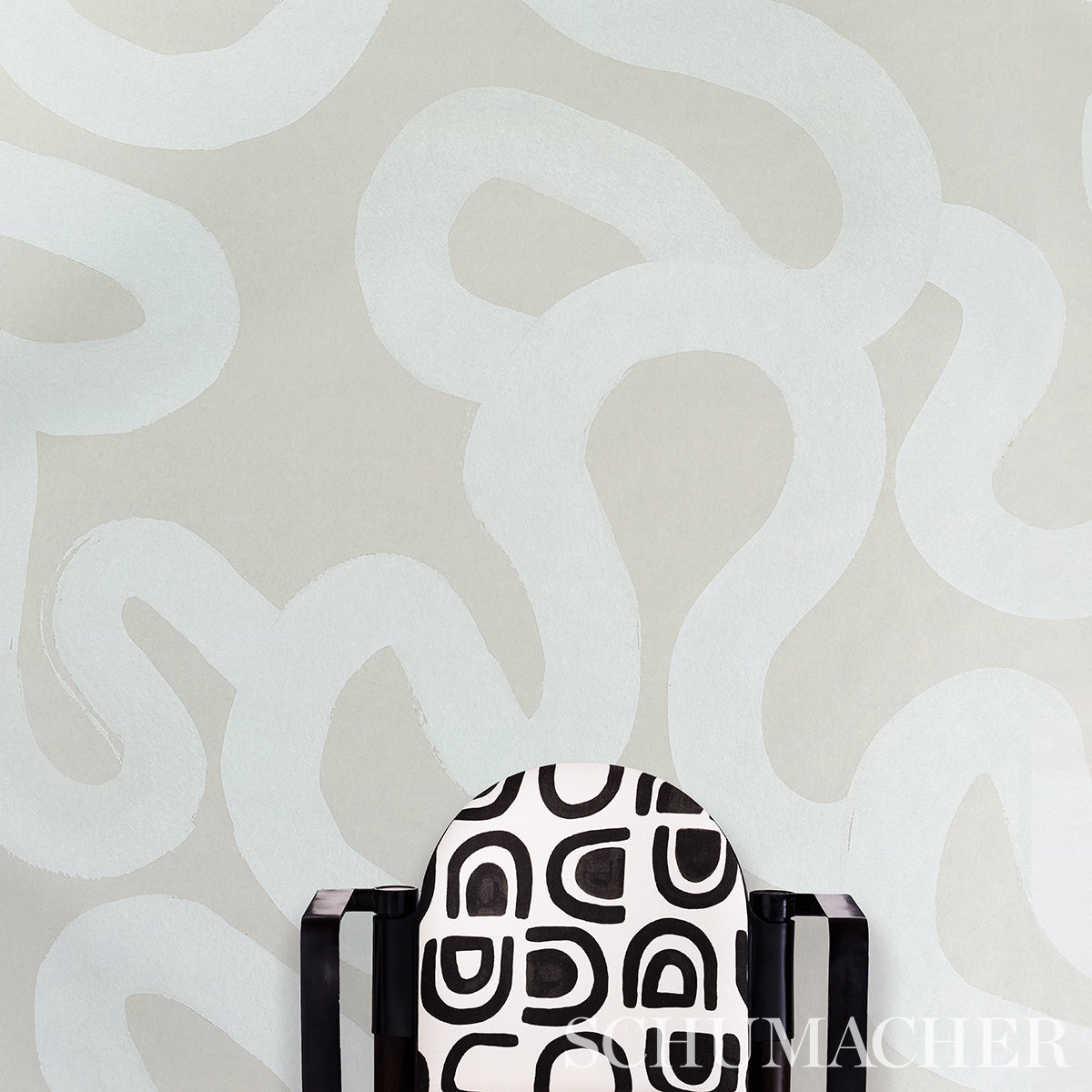 Accent armchair with black-and-white geometric upholstery, dark wood arms, placed against a beige abstract wall.