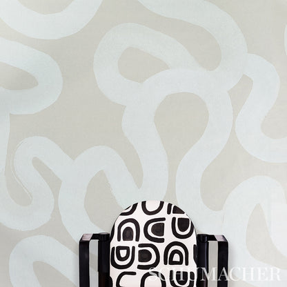 Accent armchair with black-and-white geometric upholstery, dark wood arms, placed against a beige abstract wall.