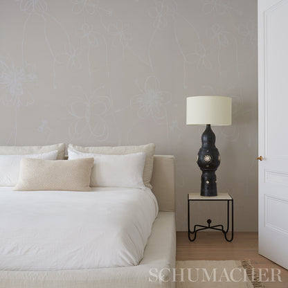 White bedding, beige lumbar pillow, black lamp with cream shade on a metal side table; soft gray floral wallpaper.