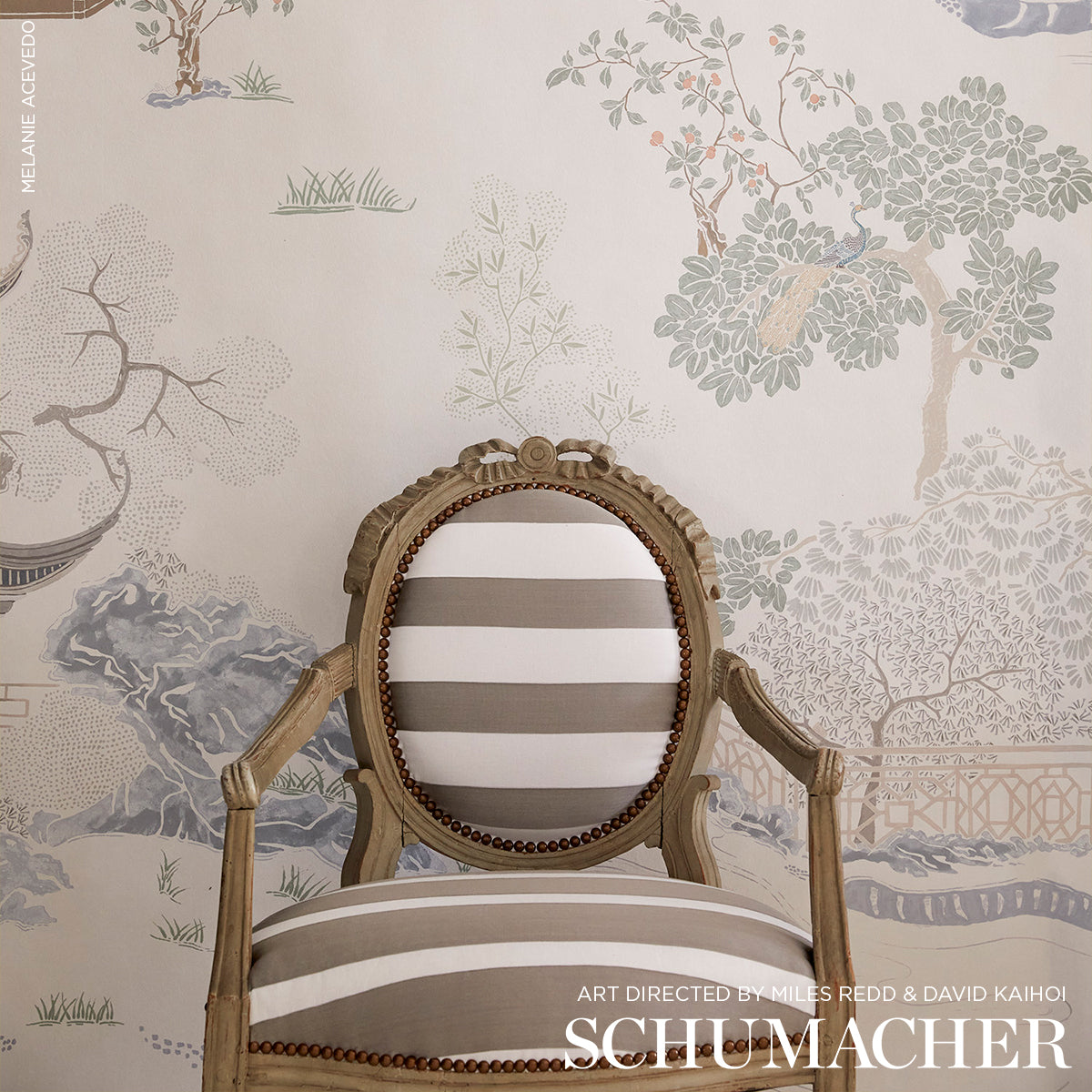 Oval-back carved wooden armchair in antique brown with beige and white striped upholstery and brass nailhead trim.