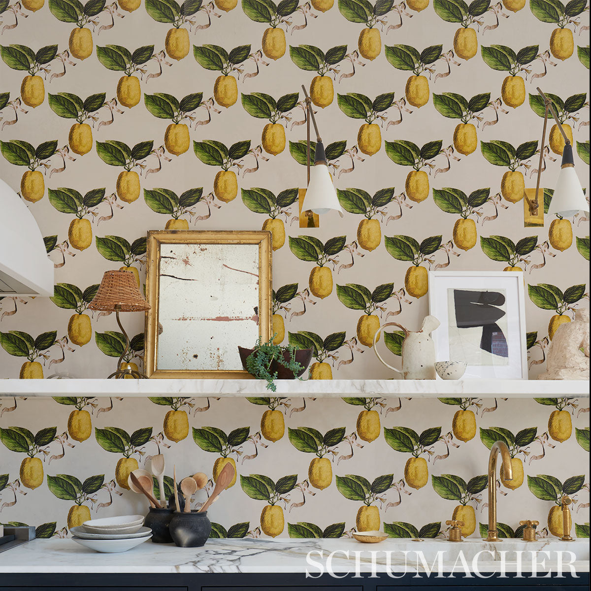Kitchen with lemon-pattern wallpaper, white shelves, marble countertop, framed art, gold faucet, and hanging pendant lights.