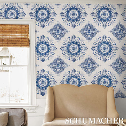 Beige curved-armchair in front of blue and white damask wallpaper, window with a bamboo blind.