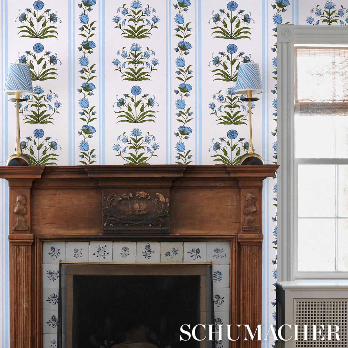 Blue floral wallpaper with vertical stripes, shown with a wooden mantel and blue lamps.