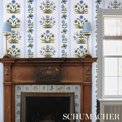 Blue floral wallpaper with vertical stripes, shown with a wooden mantel and blue lamps.