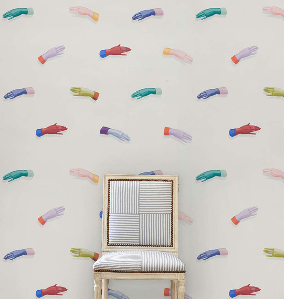 Wall covered in a pattern of multicolored hands; a light wood chair with striped upholstery sits center.