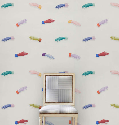 Wall covered in a pattern of multicolored hands; a light wood chair with striped upholstery sits center.