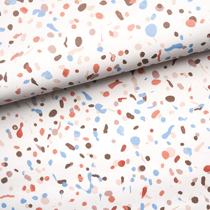Rolled backdrop fabric featuring terrazzo-inspired speckled print in blue, peach, pink, and brown.