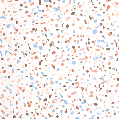 Pastel terrazzo speckle pattern with peach, blue and brown chips on a white background.