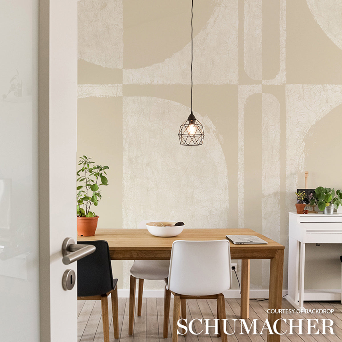 Wood dining table with white and black chairs, geometric pendant light, abstract wall art, potted plants and white console.