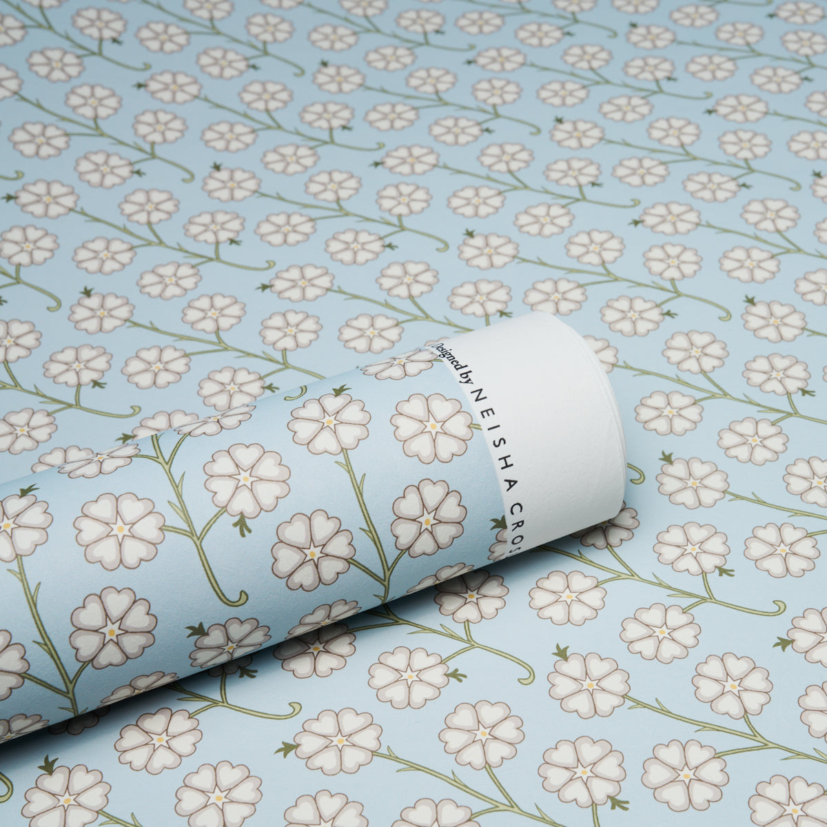Light blue wallpaper featuring white five-petaled flowers and green stems; rolled sheet with botanical print.