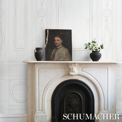 White decorative panel with an ornate arch on a light patterned wall, featuring a dark framed painting between two black vases, one with greenery.