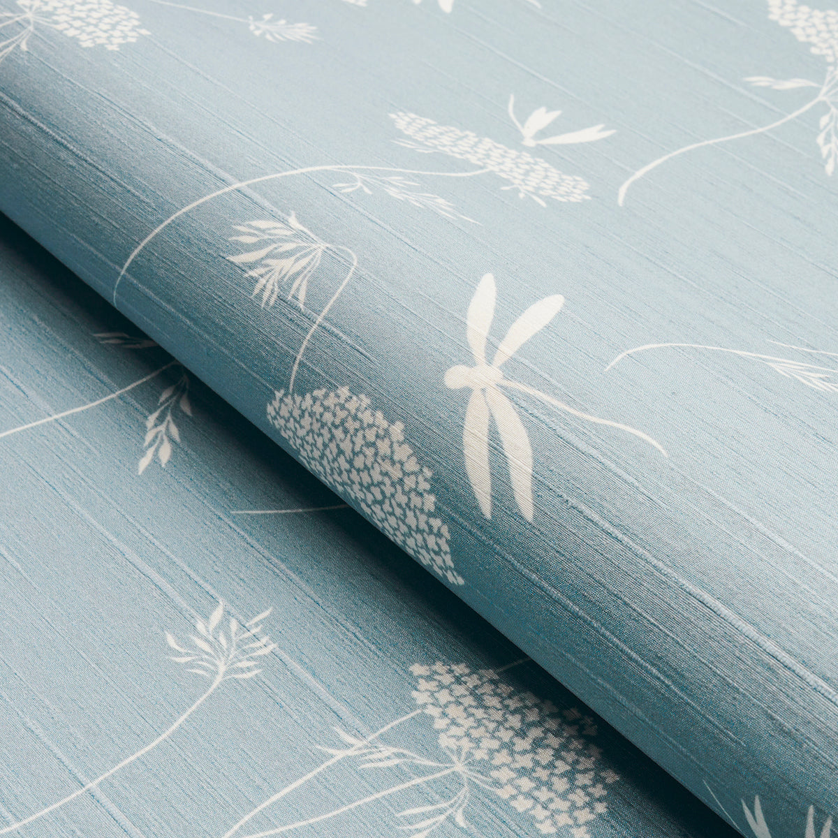 Soft blue wallcovering with white botanical and dragonfly prints, rolled at the edge, linen-like texture.