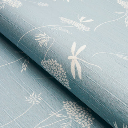 Soft blue wallcovering with white botanical and dragonfly prints, rolled at the edge, linen-like texture.