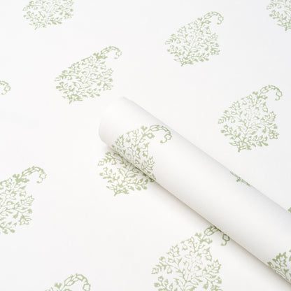 White wallpaper with a pale green paisley leaf pattern, rolled up at the corner.