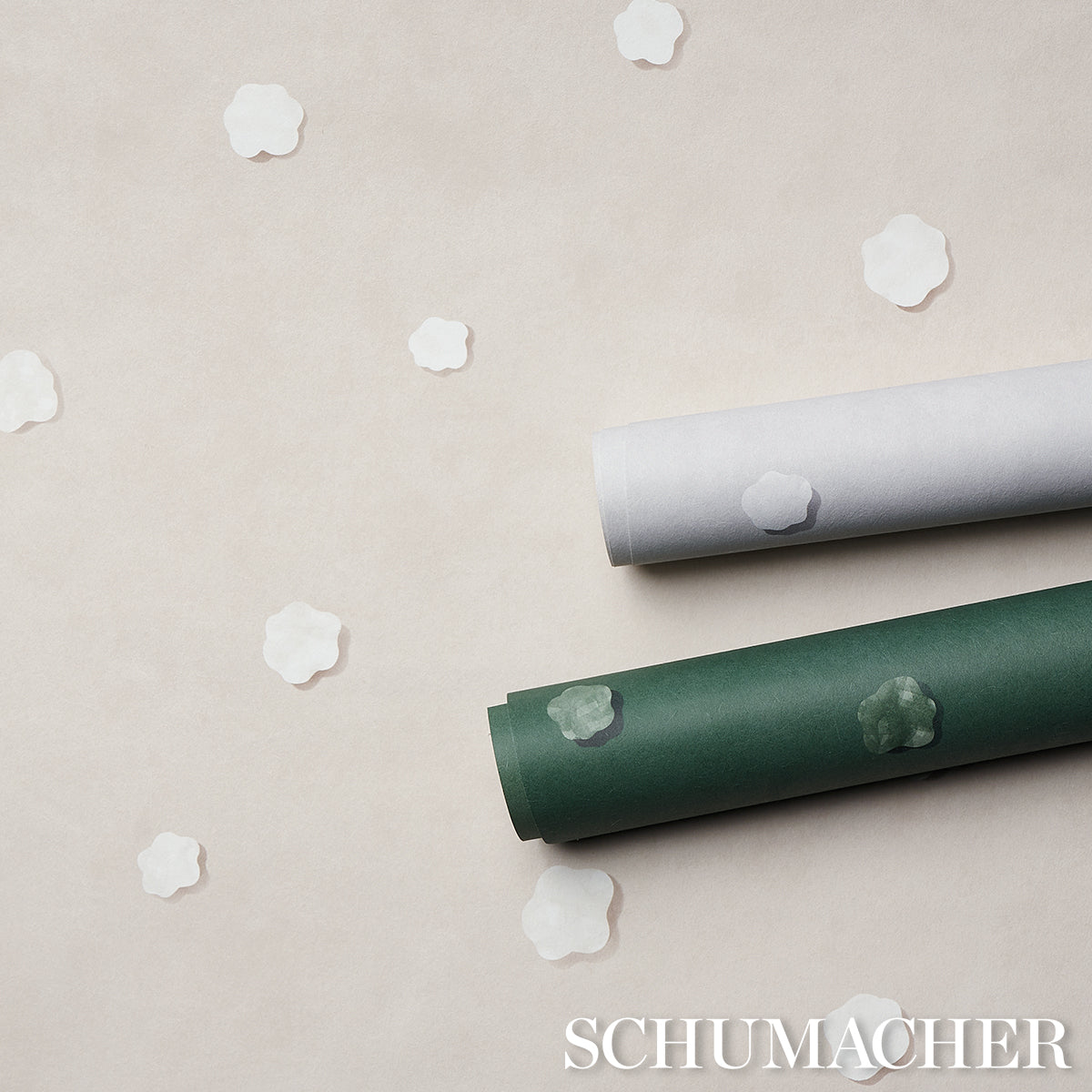 Two rolled backdrops, gray and dark green, on a beige surface with white flower-shaped confetti.