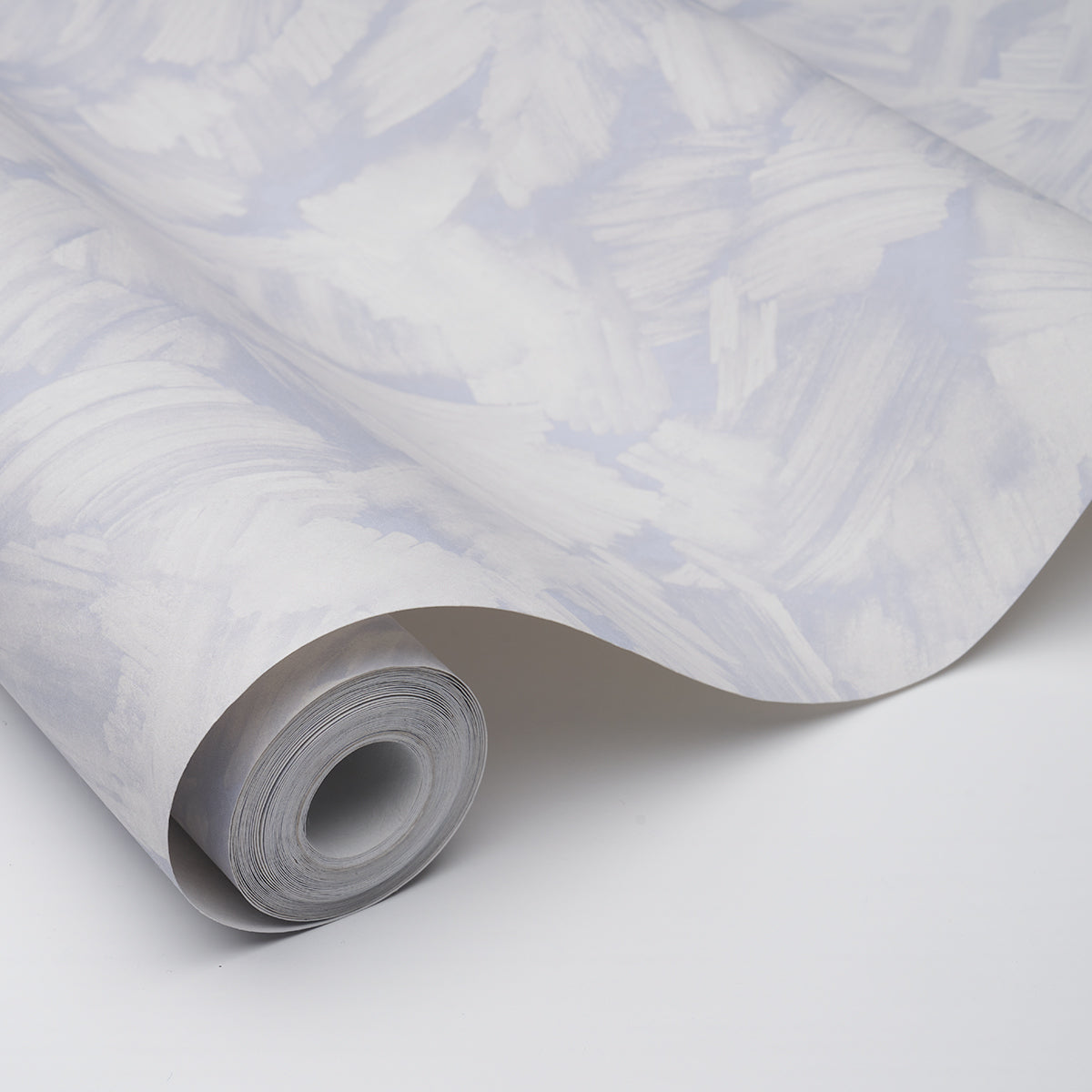 Roll of light gray wallpaper with abstract white brushstroke pattern, partially unrolled with a curved edge.