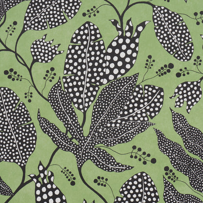Green fabric featuring black leaves with white polka dots and delicate berry clusters in a bold botanical print.
