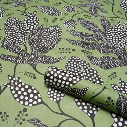 Green fabric with black and white botanical leaf print; rolled corner reveals dotted reverse.