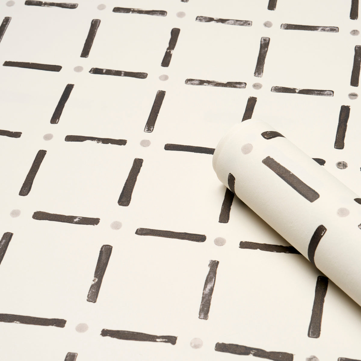 Black wallpaper with a grid of short dashes and tiny gray dots; rolled sample shows a modern geometric pattern.