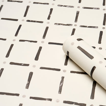 Black wallpaper with a grid of short dashes and tiny gray dots; rolled sample shows a modern geometric pattern.