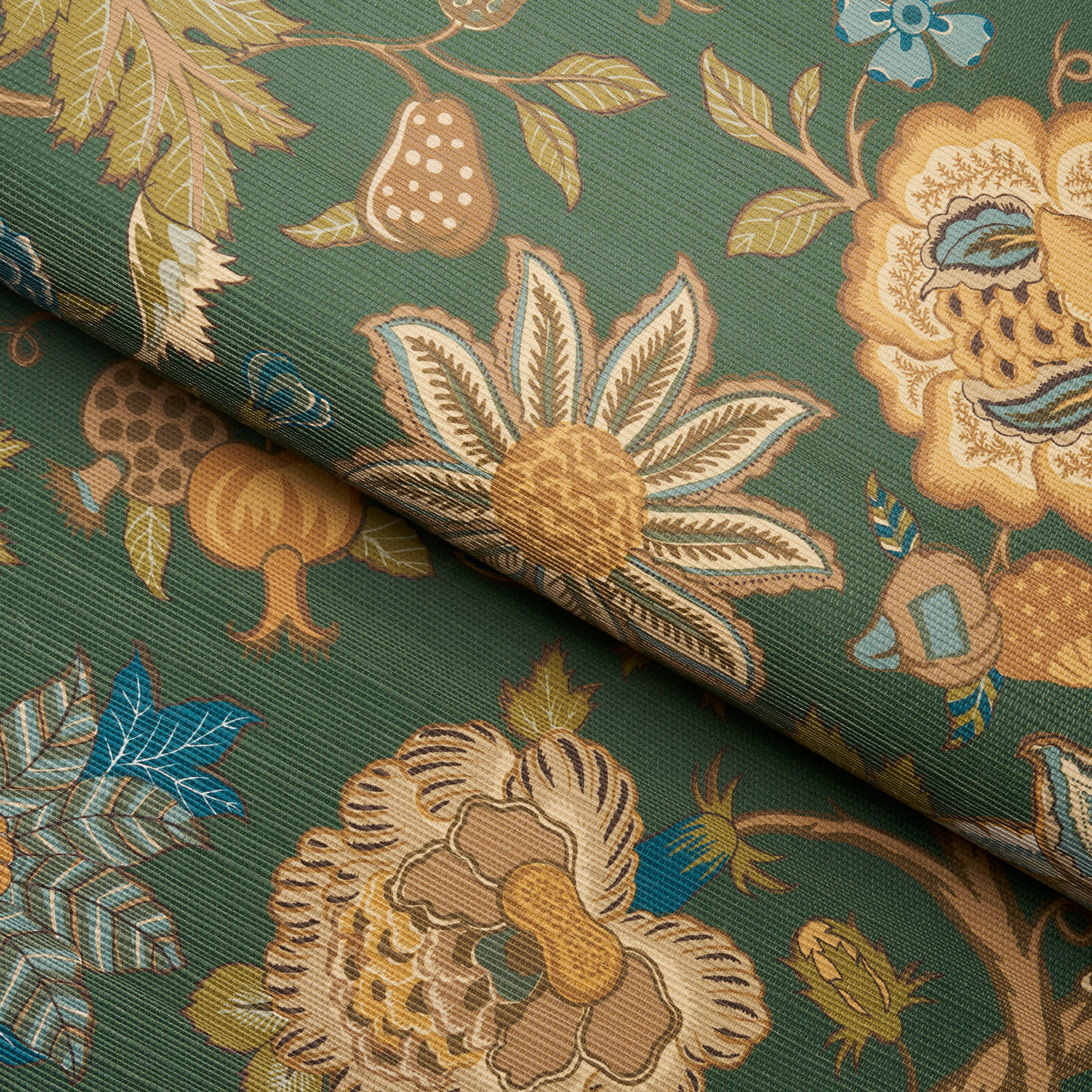 Green tree-of-life motif on a juniper sisal rug, with cream detailing, gold-tan flowers and blue accents, rolled up.