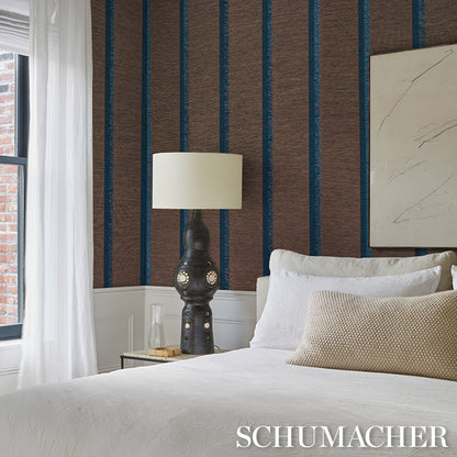 Bedroom with brown and blue striped wallpaper, white bedding, beige lumbar pillow, ornate black lamp on a nightstand.