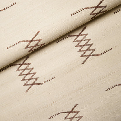 Beige sisal embroidery fabric with hazel on ivory geometric diamond pattern; folded edge, soft textile texture.