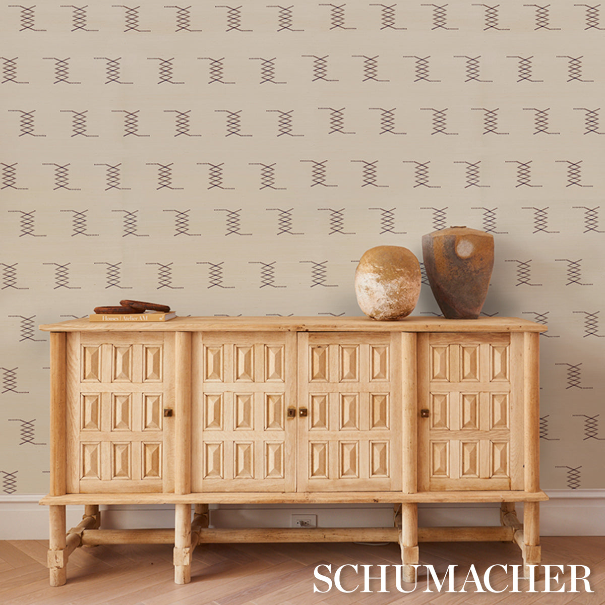 Sisal embroidery rug in hazel on ivory, shown with rustic light wood furniture, two earthy ceramic vases, and beige geometric wallpaper.