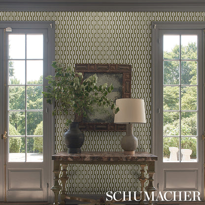 Rustic wooden console table with a greenery vase and beige lamp, ornate mirror, set against geometric Schumacher wallpaper.