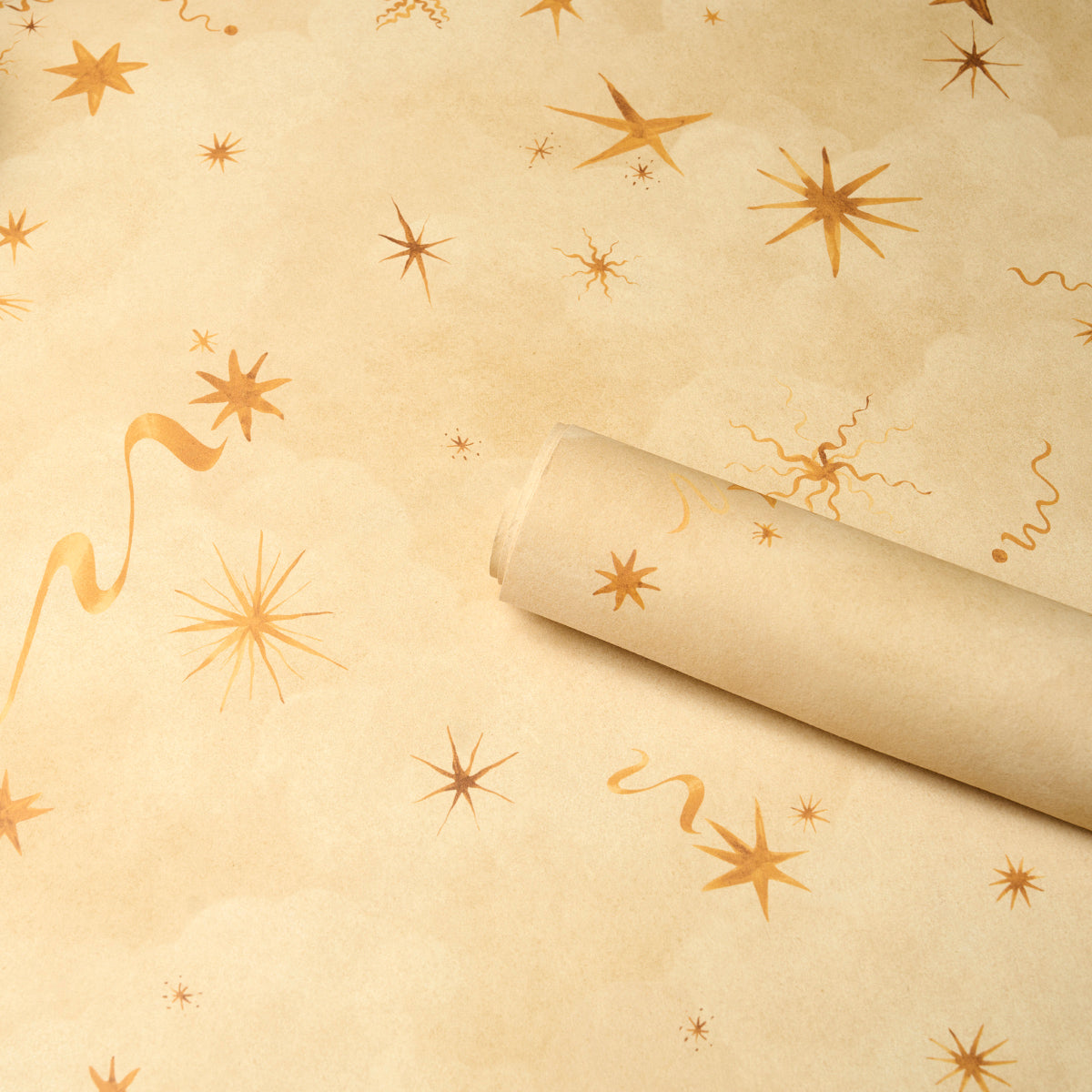 Beige wrapping paper with orange starbursts and curling ribbons; a rolled sheet lies diagonally across the festive background.