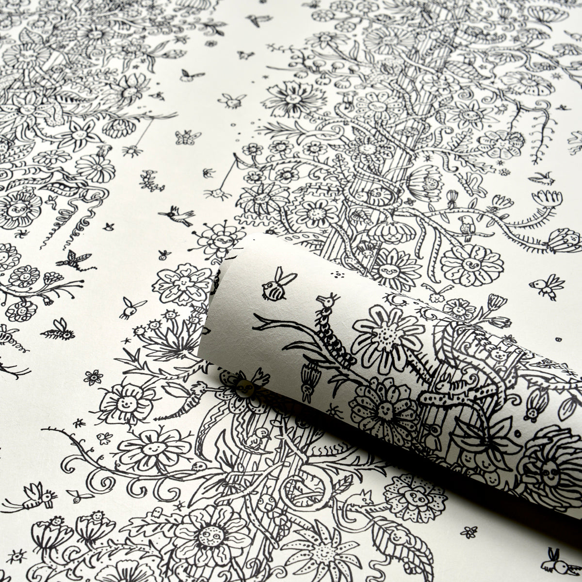 White wallpaper with dense black botanical line art of flowers and vines; rolled corner shows pattern.