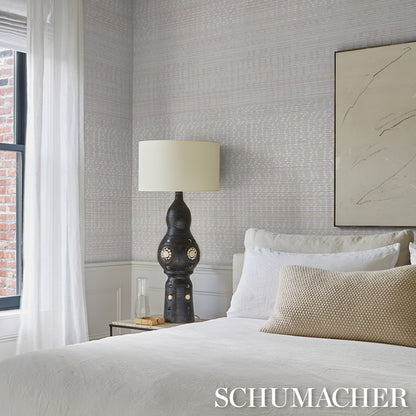 Neutral room featuring waterlily wallcovering in silver on the walls, with a dark ceramic lamp and cream shade, white bedding, and a beige throw pillow.