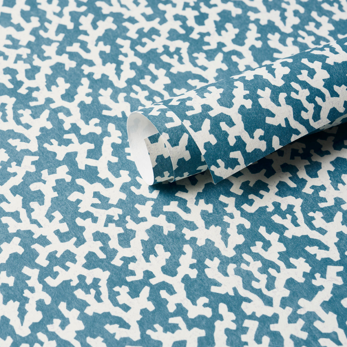 Teal fabric with white irregular coral pattern, rolled.