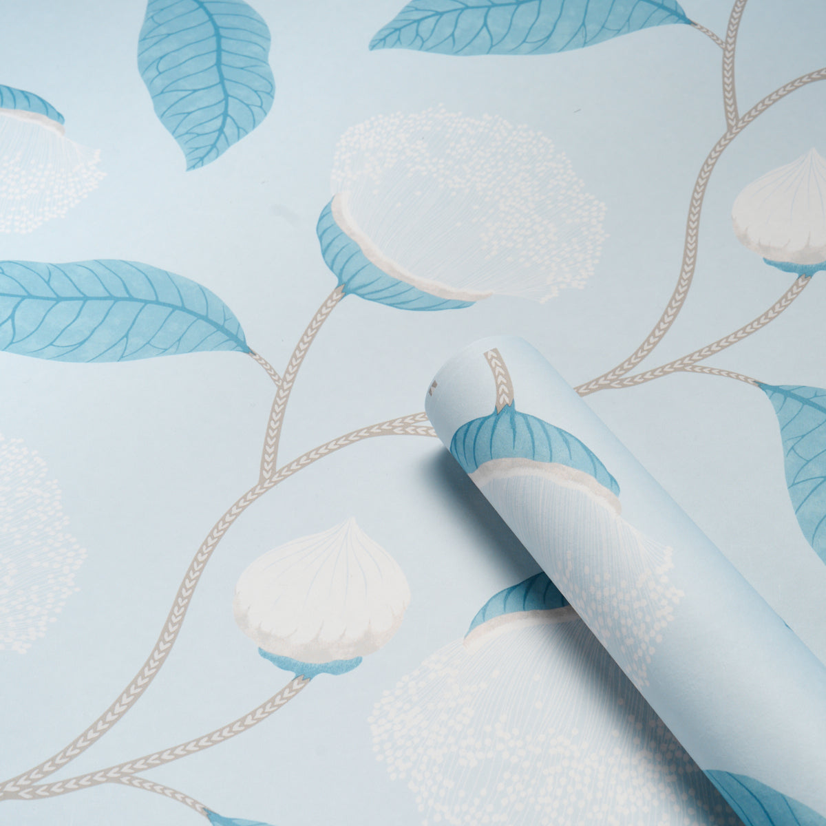 Light blue wallpaper with blue leaves, beige vines and white floral clusters; rolled sample.