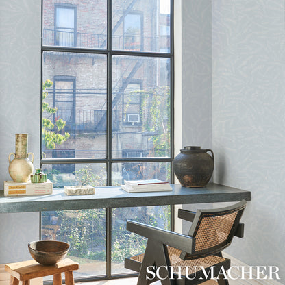 Industrial desk by large window with metal frame, grey top; wicker chair, ceramic vases, books, wooden bowl.
