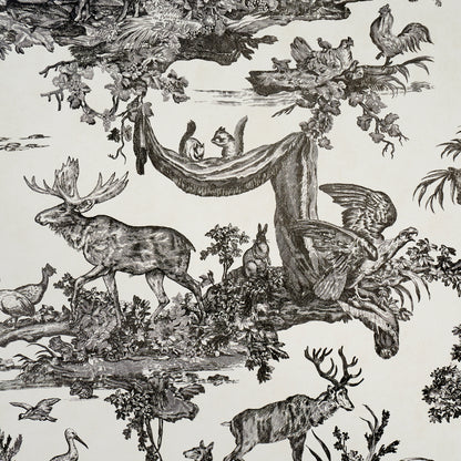 Monochrome black-on-white toile print on fabric: deer, moose, birds in a forest with a man in a hammock, engraving style.