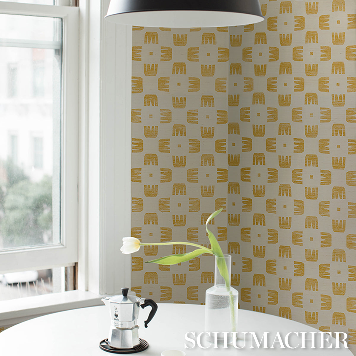 Bright kitchen nook: white round table with moka pot, tulip in a glass vase, sisal maize wallpaper, black pendant lamp.