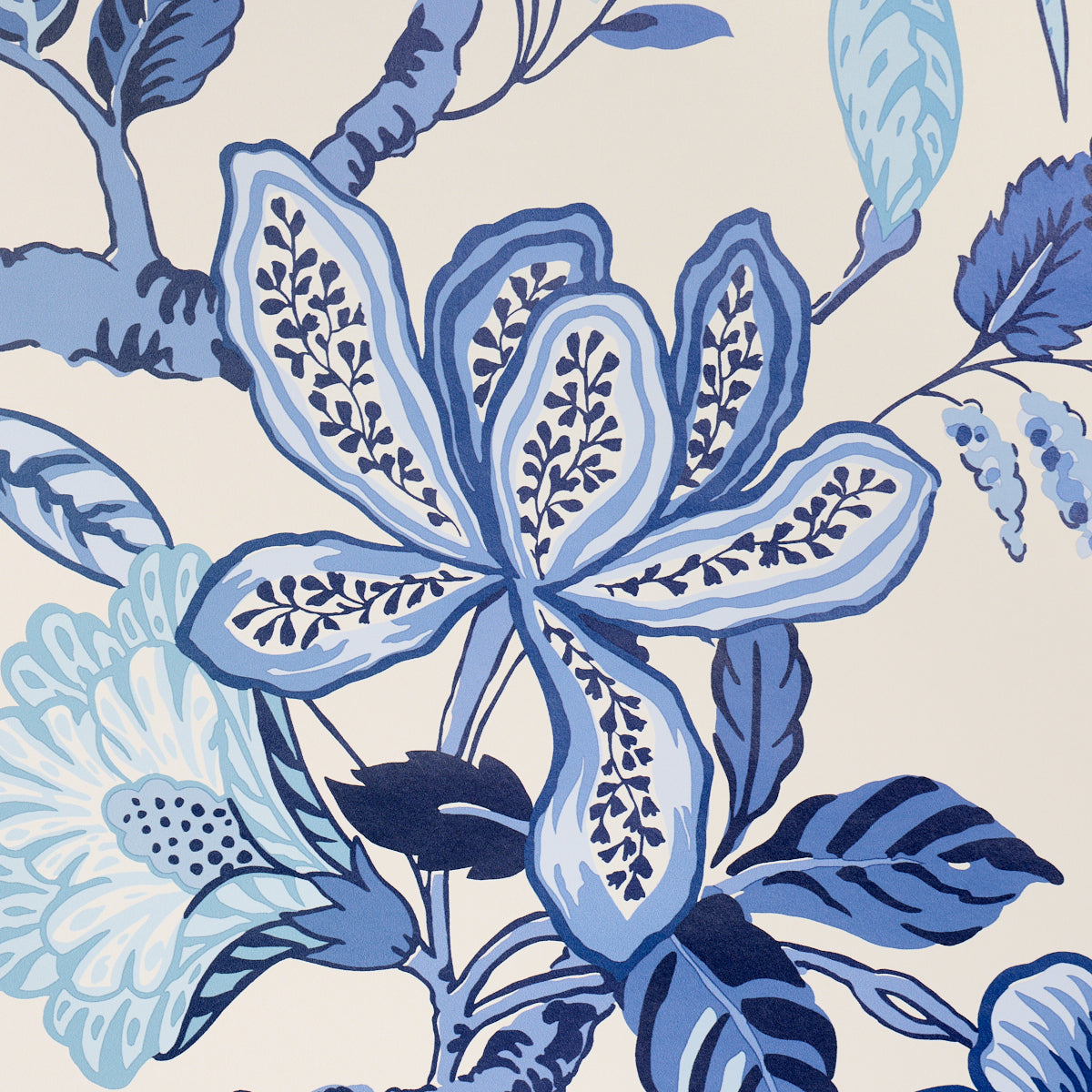 Blue botanical floral pattern on beige background; large petal shapes and leaves in navy and sky blues.
