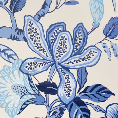 Blue botanical floral pattern on beige background; large petal shapes and leaves in navy and sky blues.