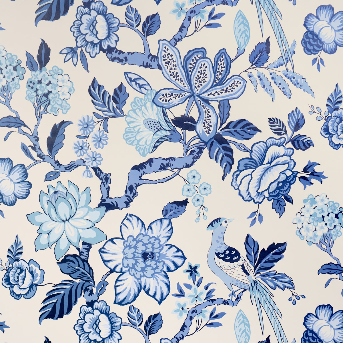 Blue and white botanical pattern with large flowers, leaves and a perched bird on a cream background.