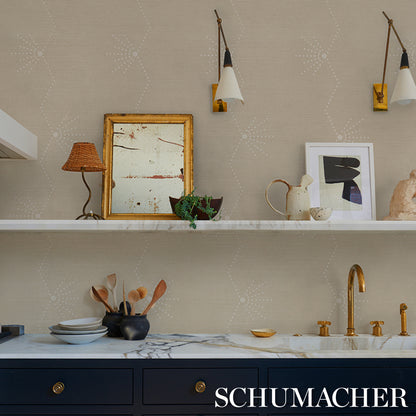 Beige patterned kitchen with white shelf, brass faucet, navy cabinets, marble countertop, framed art and decorative items.