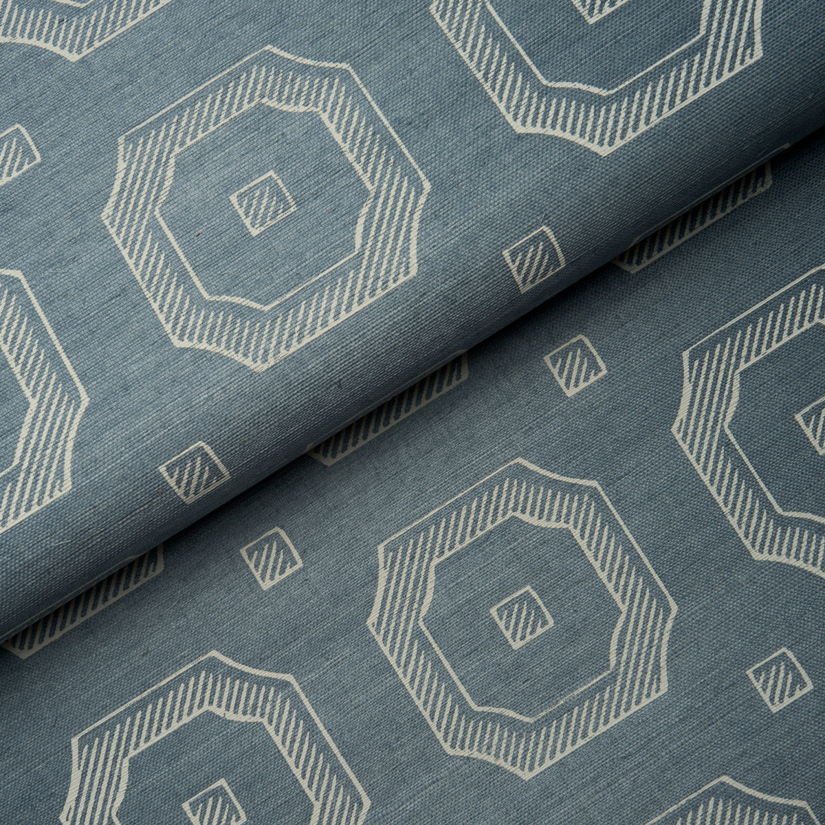 Blue fabric with white geometric octagon motifs and small square accents, folded to show repeating print.