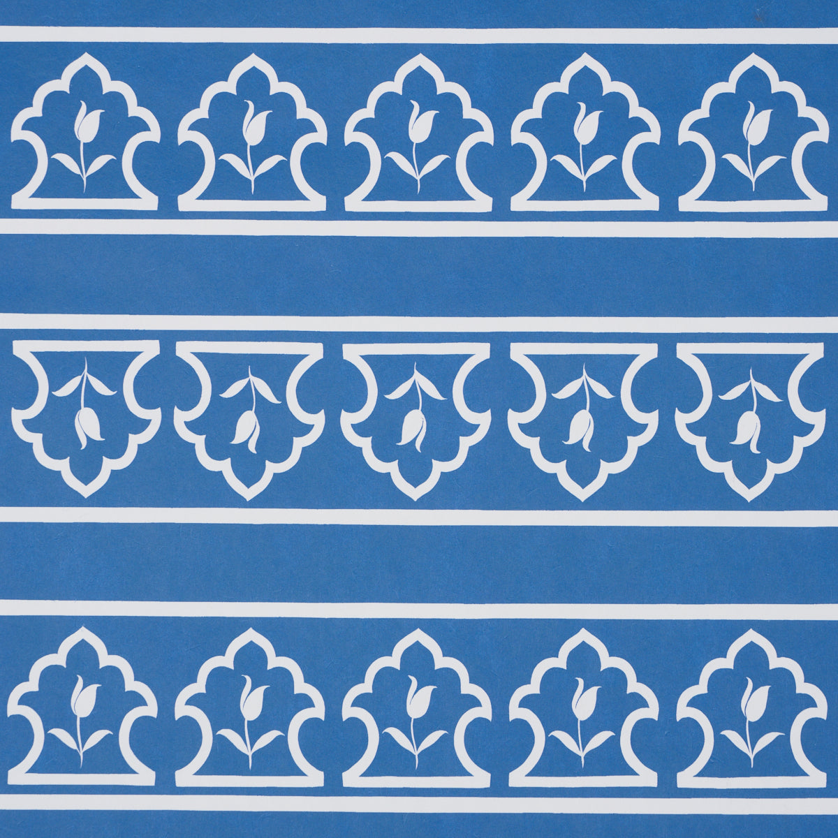 Blue background with white repeating border motifs, fleur-de-lis leaf shapes in arched panels across horizontal stripes.