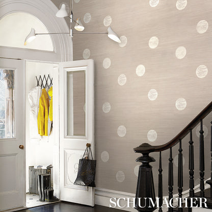 Entry hall with beige polka-dot wallpaper, white doors, dark wood railing, modern light fixture, yellow coat hanging.
