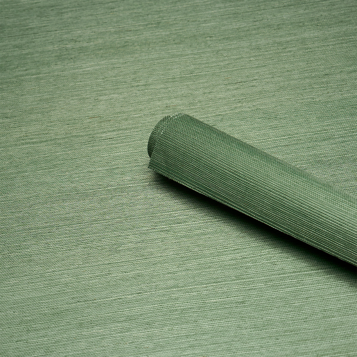 Olive green woven fabric roll with curled edge on a matching surface; versatile upholstery or craft textile.