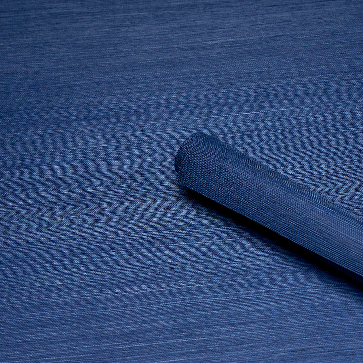 Dark blue backdrop fabric rolled into a cylinder on a textured blue background.