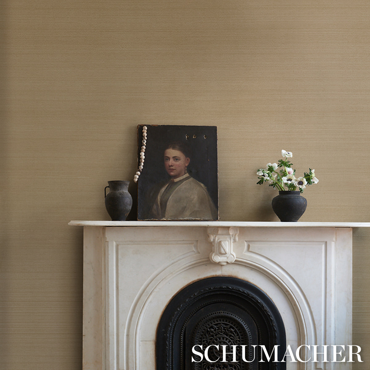 Beige wall with white marble mantel, dark portrait propped, pearl necklace draped, black vase left, bouquet in black vase right
