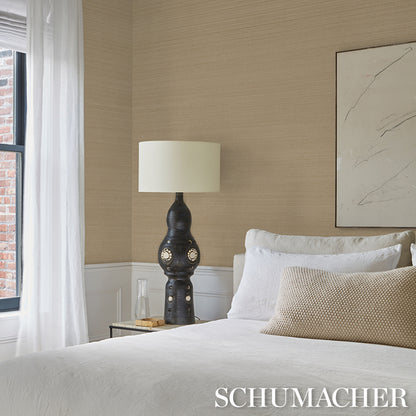 Dark ceramic table lamp with a rounded base and cream drum shade on a wood bedside table in a neutral beige bedroom.